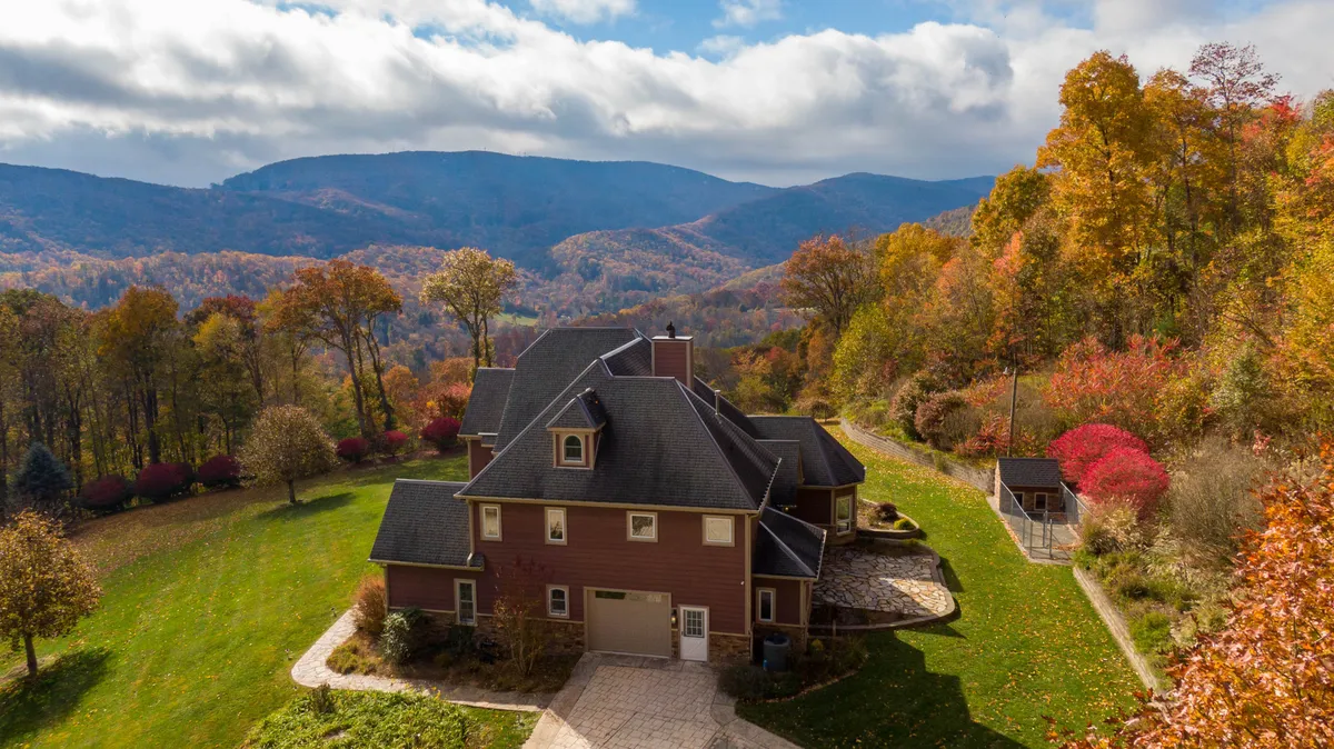This image features the house with a stunning mountain backdrop, colorful foliage, and a landscaped yard. The scene evokes a sense of immersion in the natural beauty of the High Country and highlights the property's proximity to outdoor adventures.